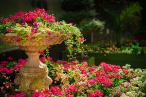 A large ceramic fountain filled with overflowing pink flowers. 