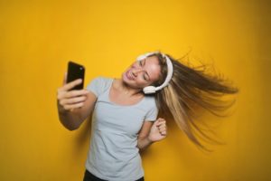 A woman taking a selfie in front of a yellow wall