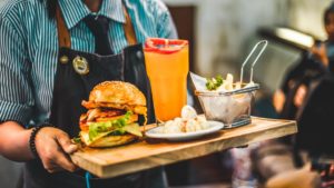 A man serving up a burger, fries, and a drink.