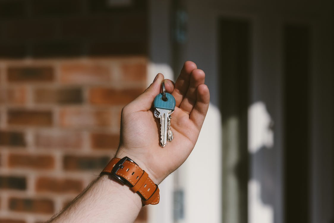 A person holding up keys to a house.