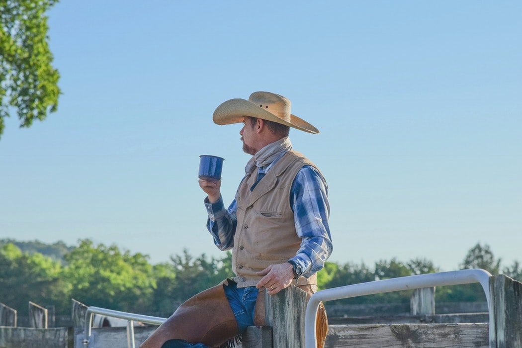 A cowboy sitting on a fence.