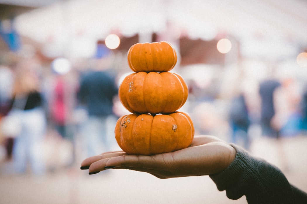 A person holding up pumpkins.