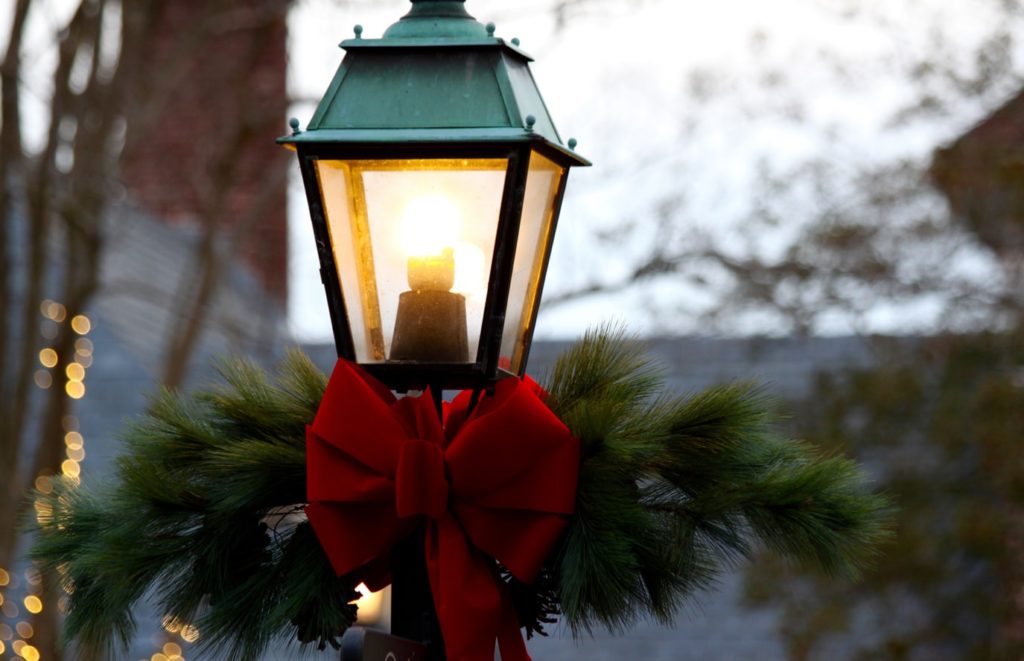 A red bow on a street light surrounded by greenery and for a home staging. 