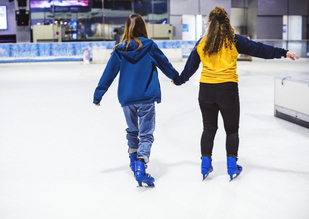 Girls ice skating at an outdoor ice rink. 