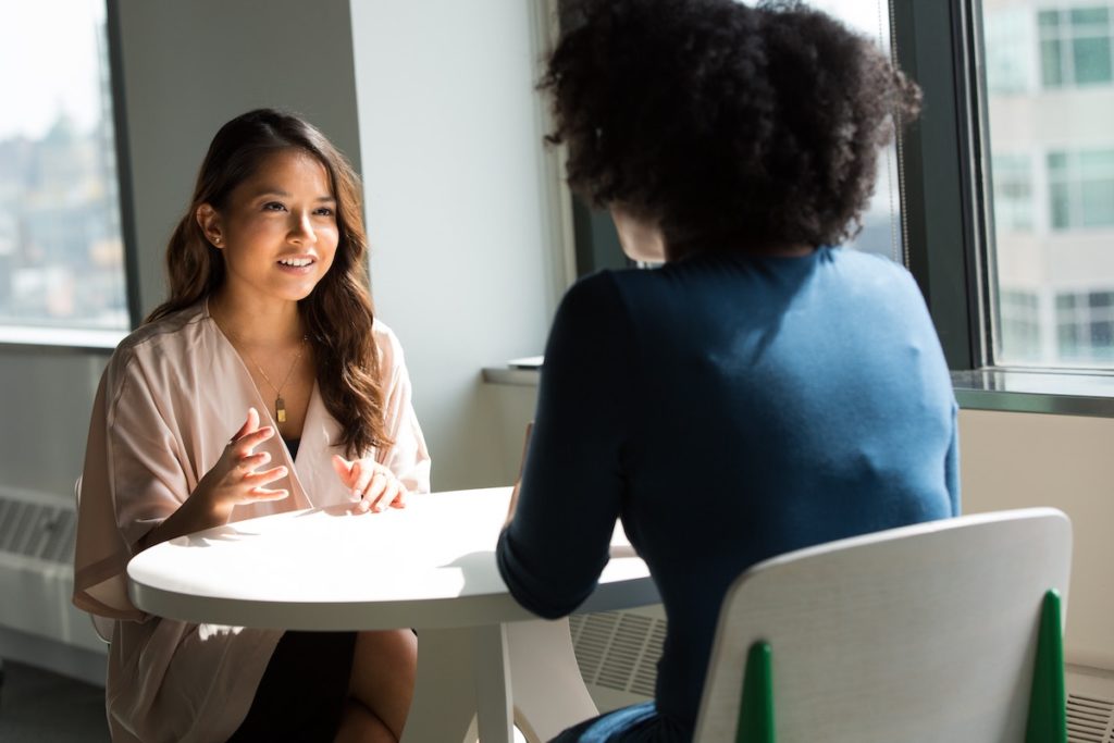 Women talking at a table about mistakes that first-time home buyers make